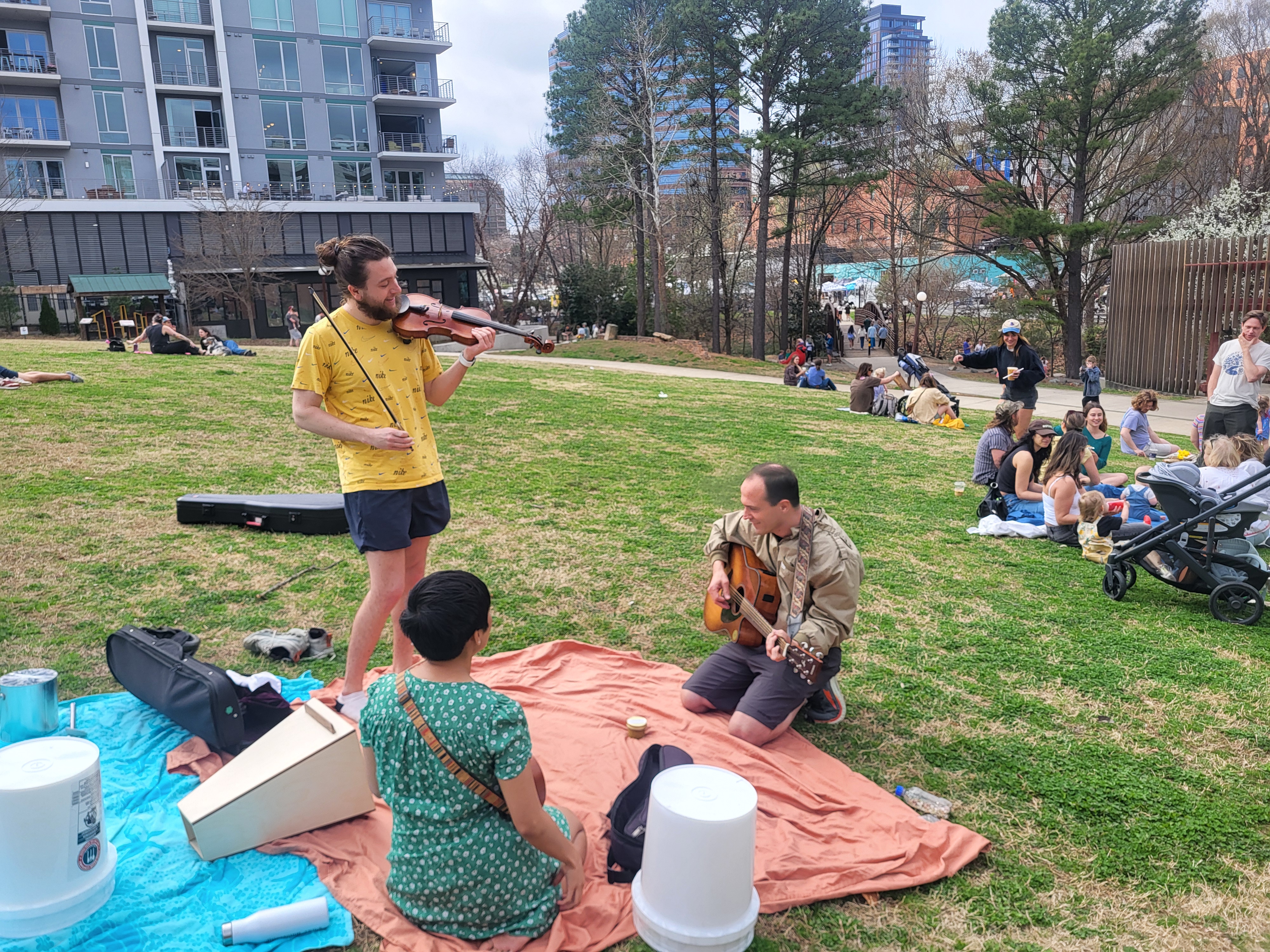 Community members playing acoustic instruments together at the jam